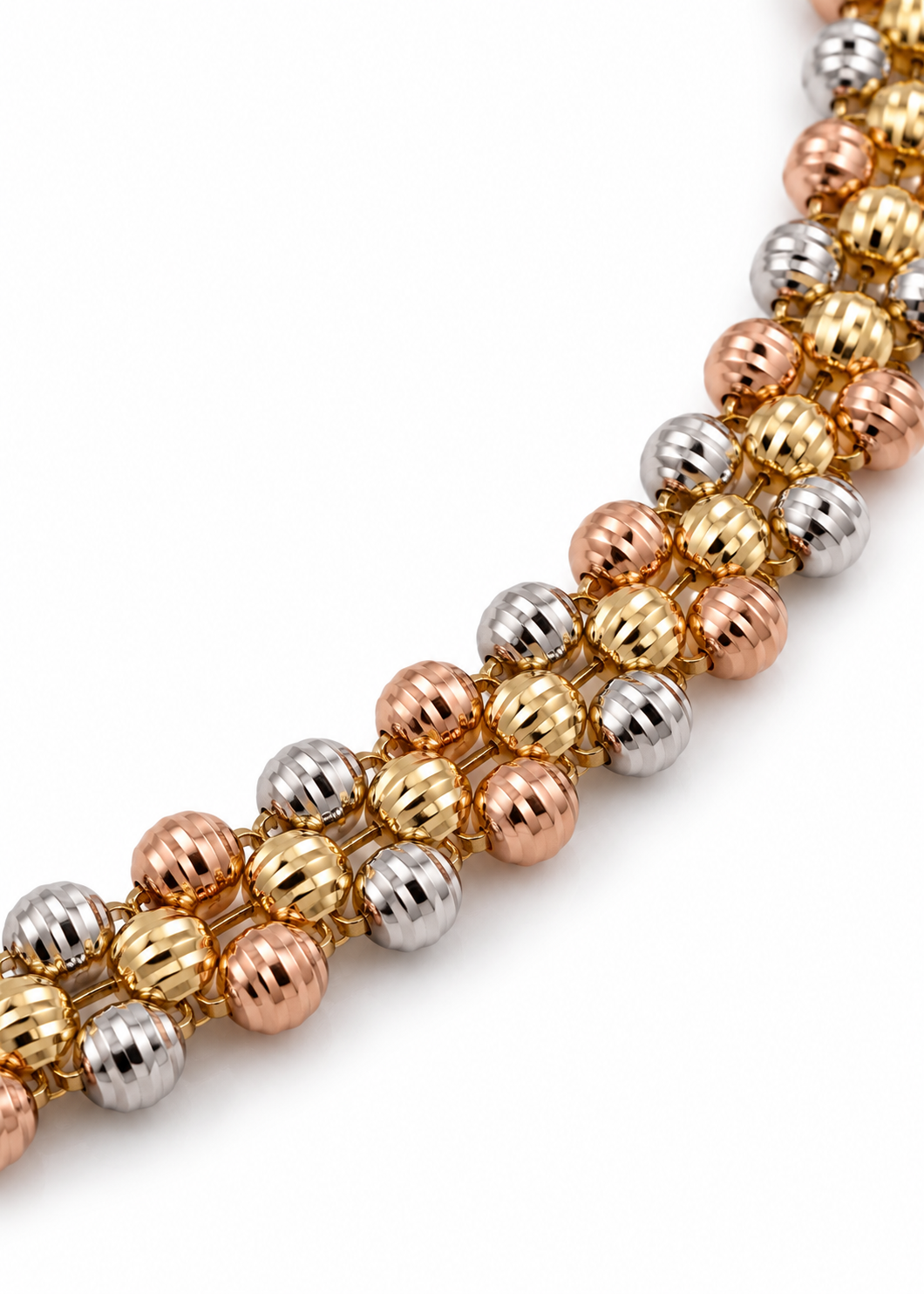 Close-up of the ribbed yellow, white, and rose gold beads on an 18K tri-color bracelet.